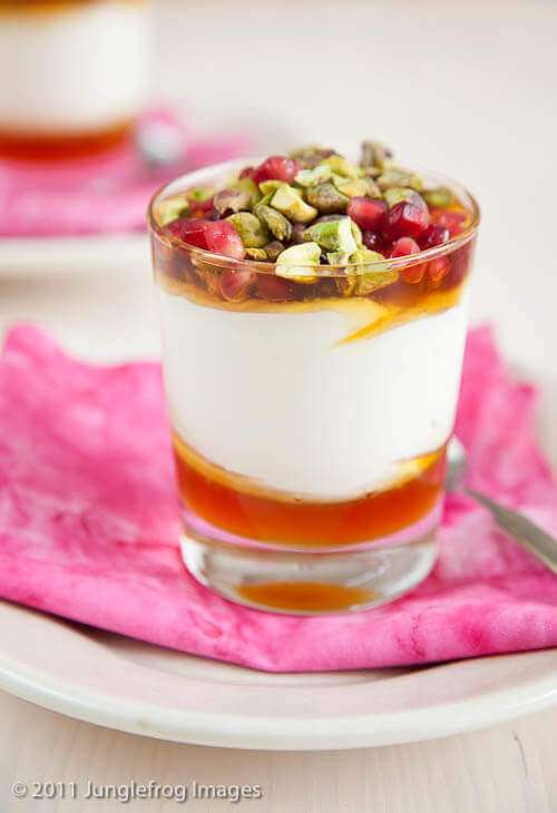 Glass of yogurt and pomegranate dessert on pink cloth