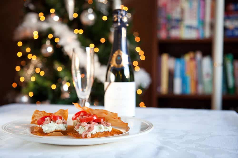 Phyllo dough snacks with guacamole and shrimps. Served in Christmas setting with a bottle of champagne