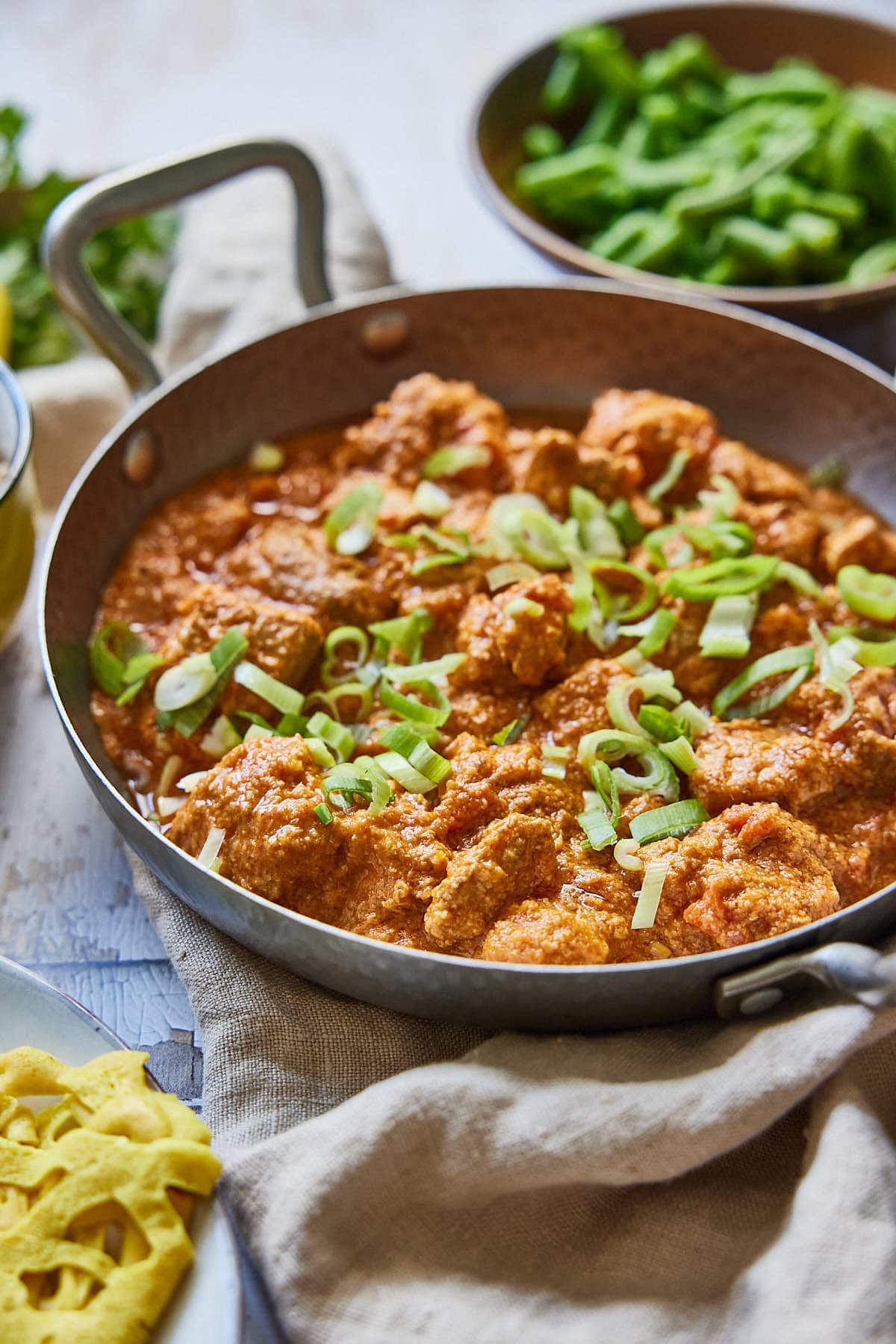Pork vindaloo dish with green beans in the background