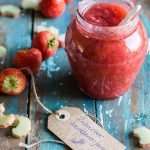 jar of rhubarb jam surrounded by strawberries