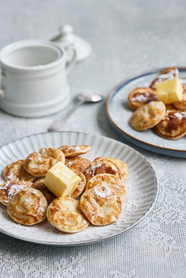 Traditional Dutch mini pancakes with butter and powdered sugar.