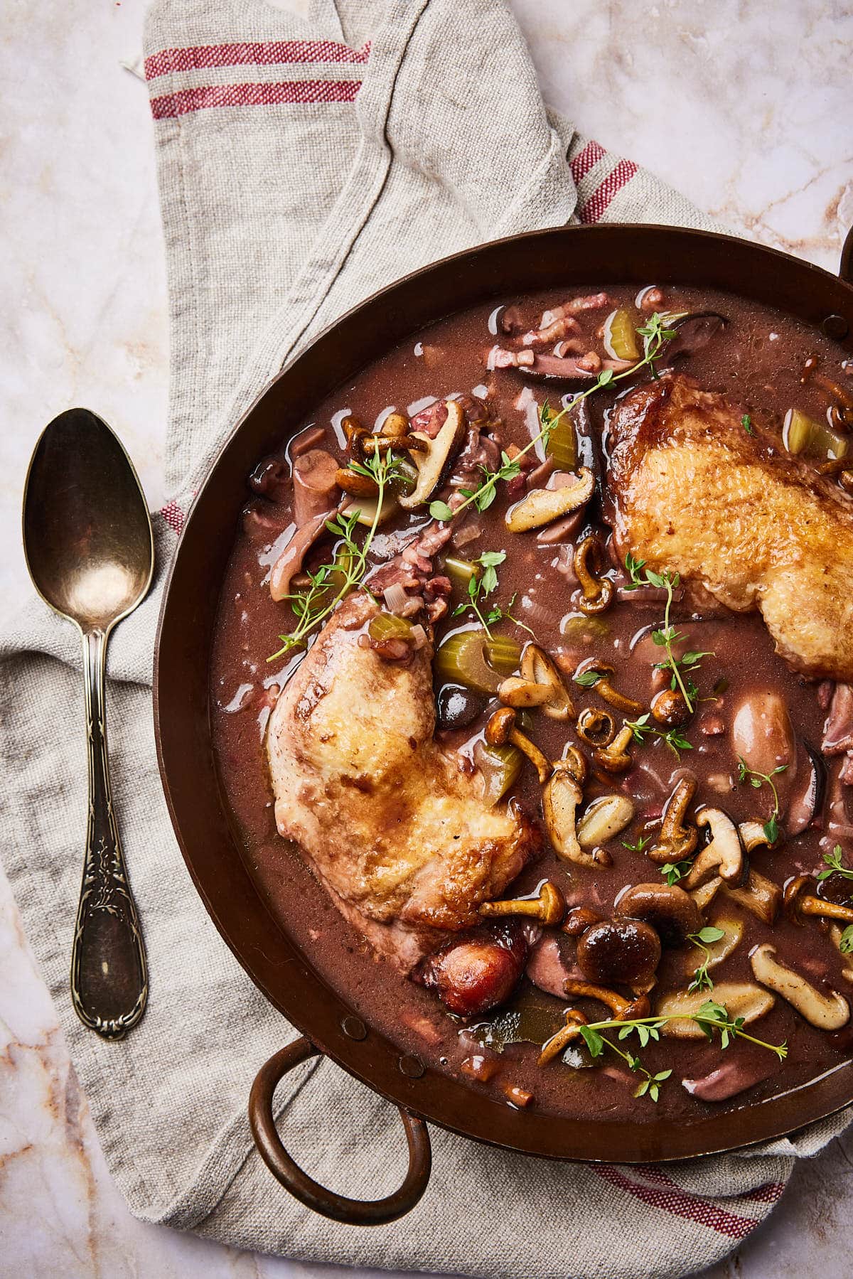 Coq au vin served in the pan with mushrooms on top