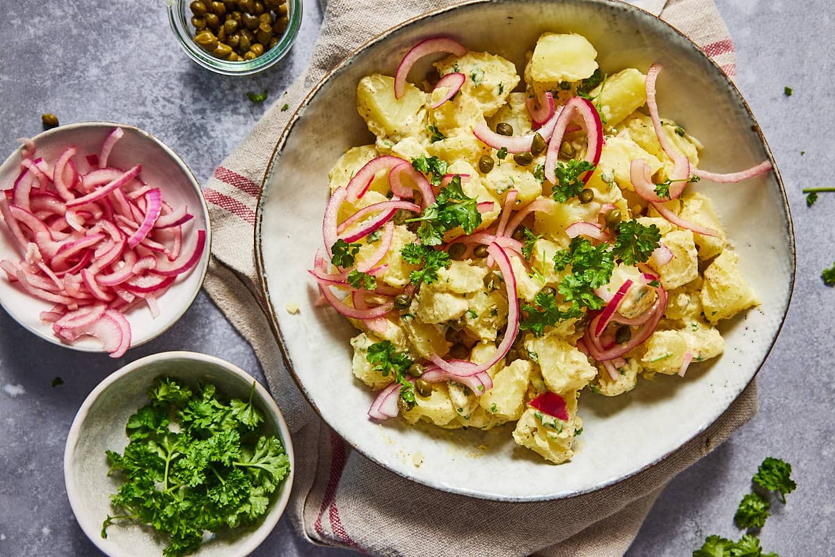 Classic potato salad with a small bowl of onions and parsley