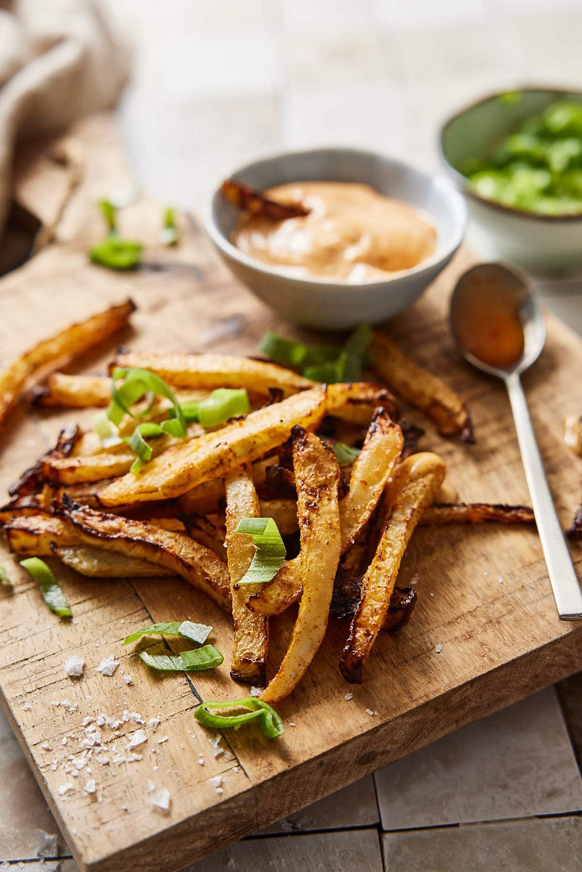 Kohlrabi fries on wooden board with dips and spring onions