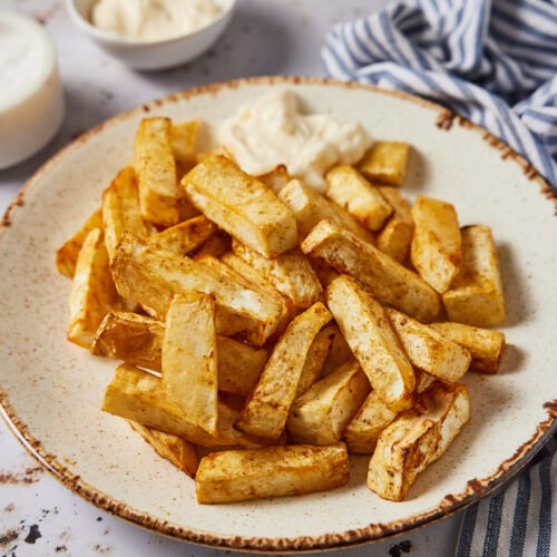 Celeriac fries on a plate with mayo in the background
