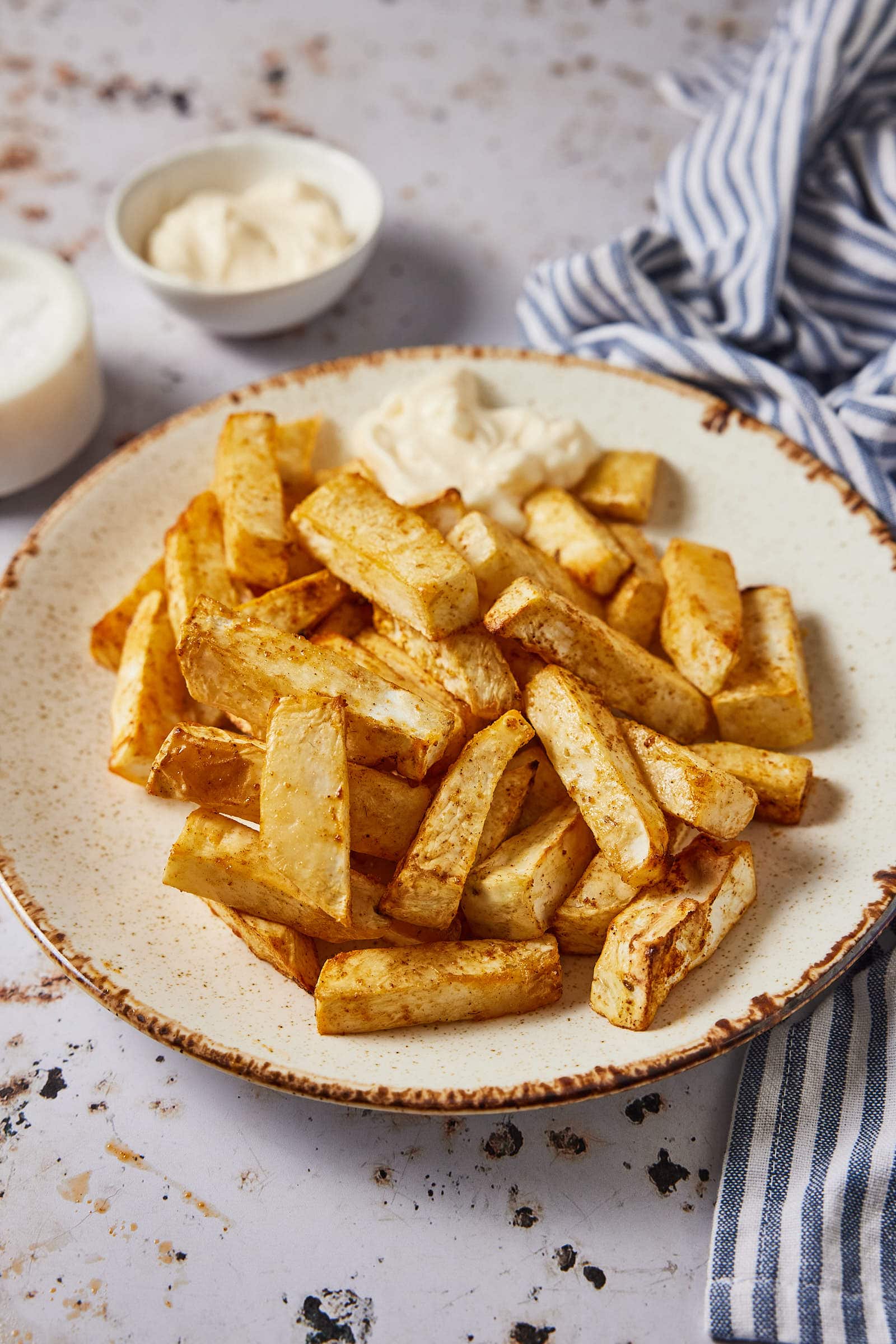 Celeriac fries on a plate with mayo in the background